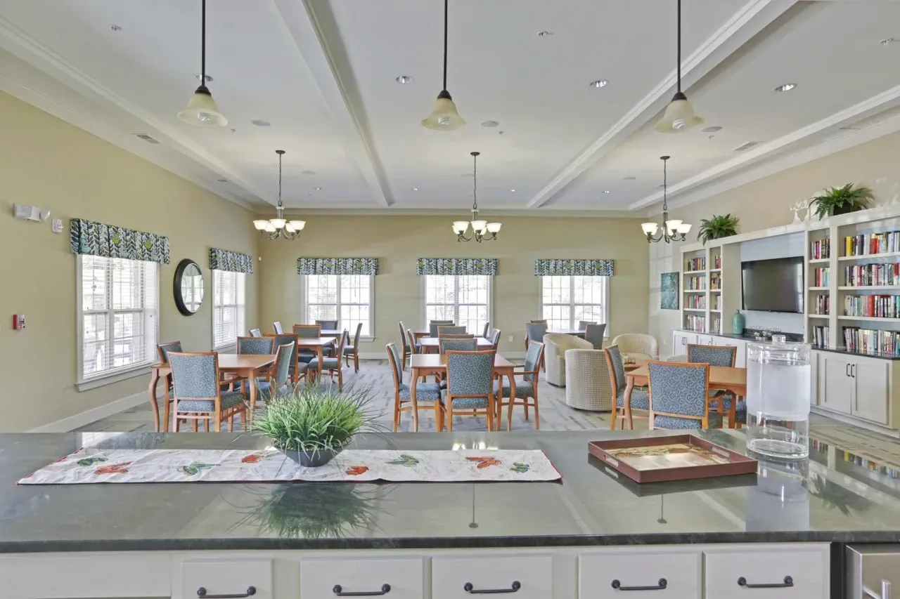 Interior of a resident clubhouse with a counter, tables, and bookshelves.