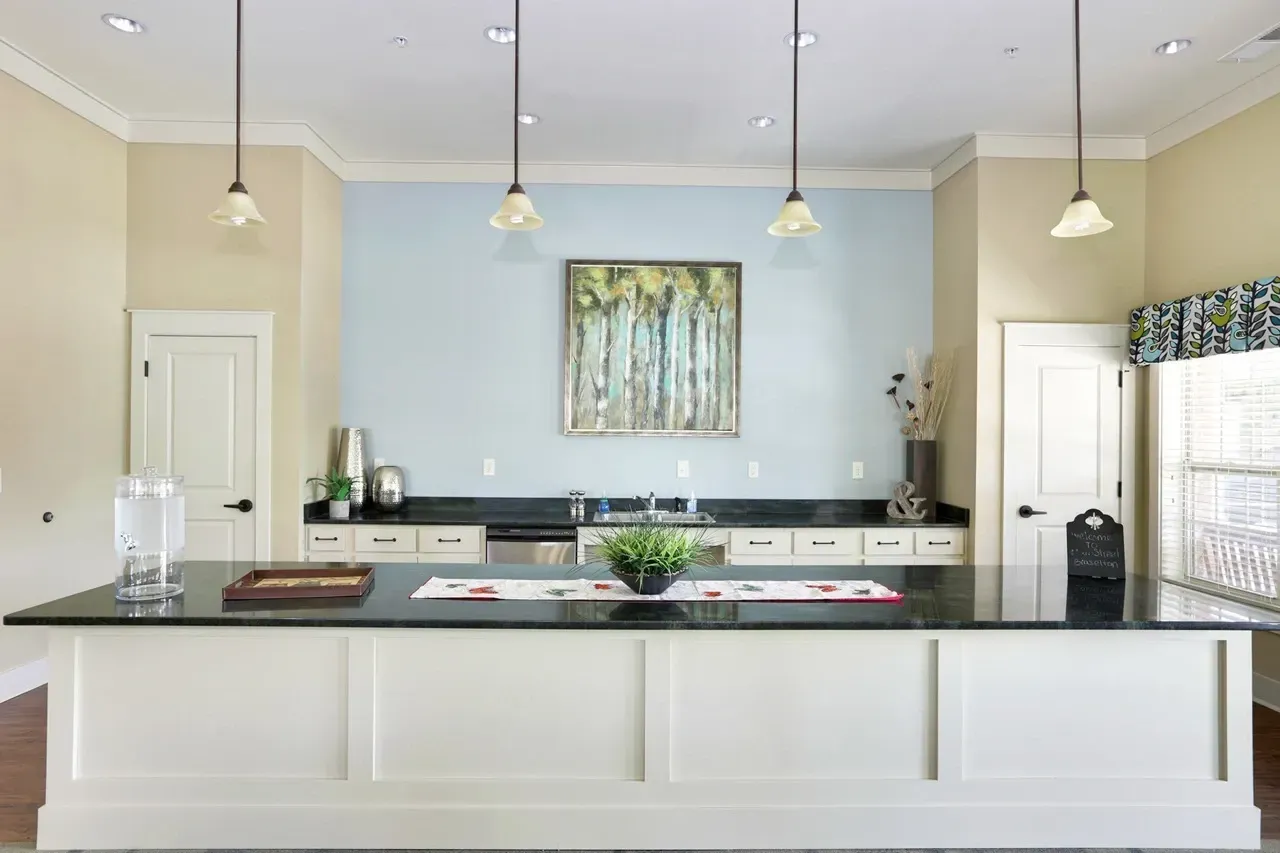 Large modern kitchen with white island, black countertops, blue accent wall and pendant lights.