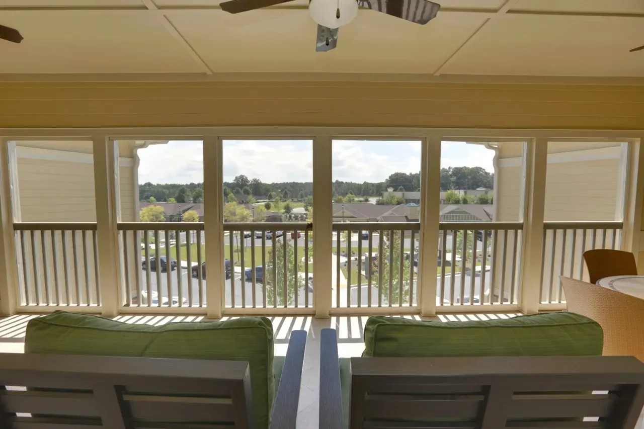 Balcony seating area with green cushions and a view of the apartment community beyond.