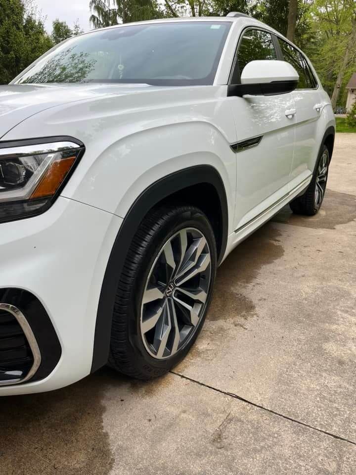 A white SUV parked on a concrete driveway, showcasing its front, driver-side wheel, and body detail.