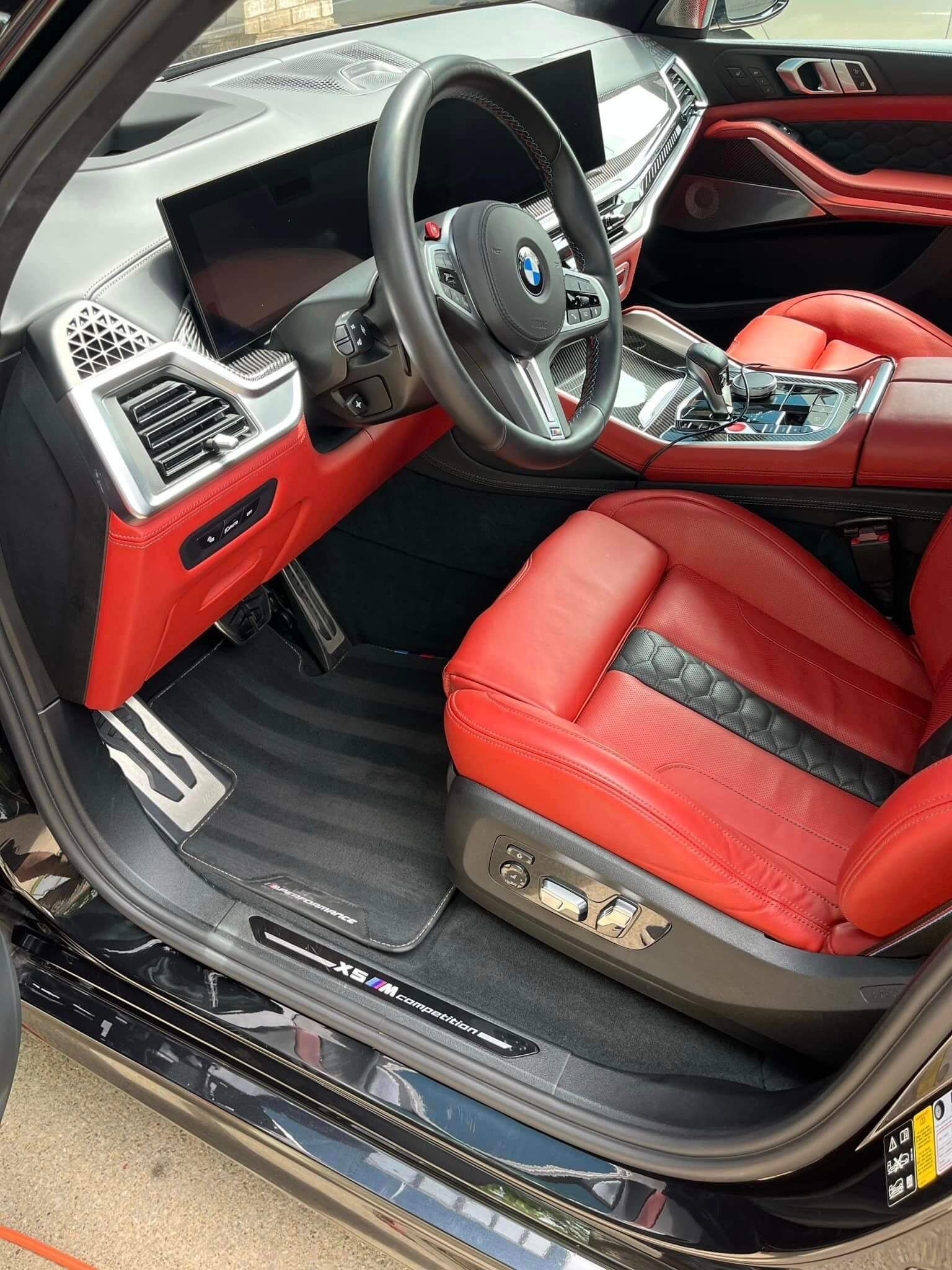 The interior of a vehicle featuring bright red leather seats, a black dashboard, and a multi-function steering wheel.
