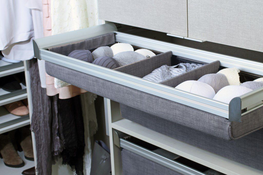 A drawer filled with clothes in a closet