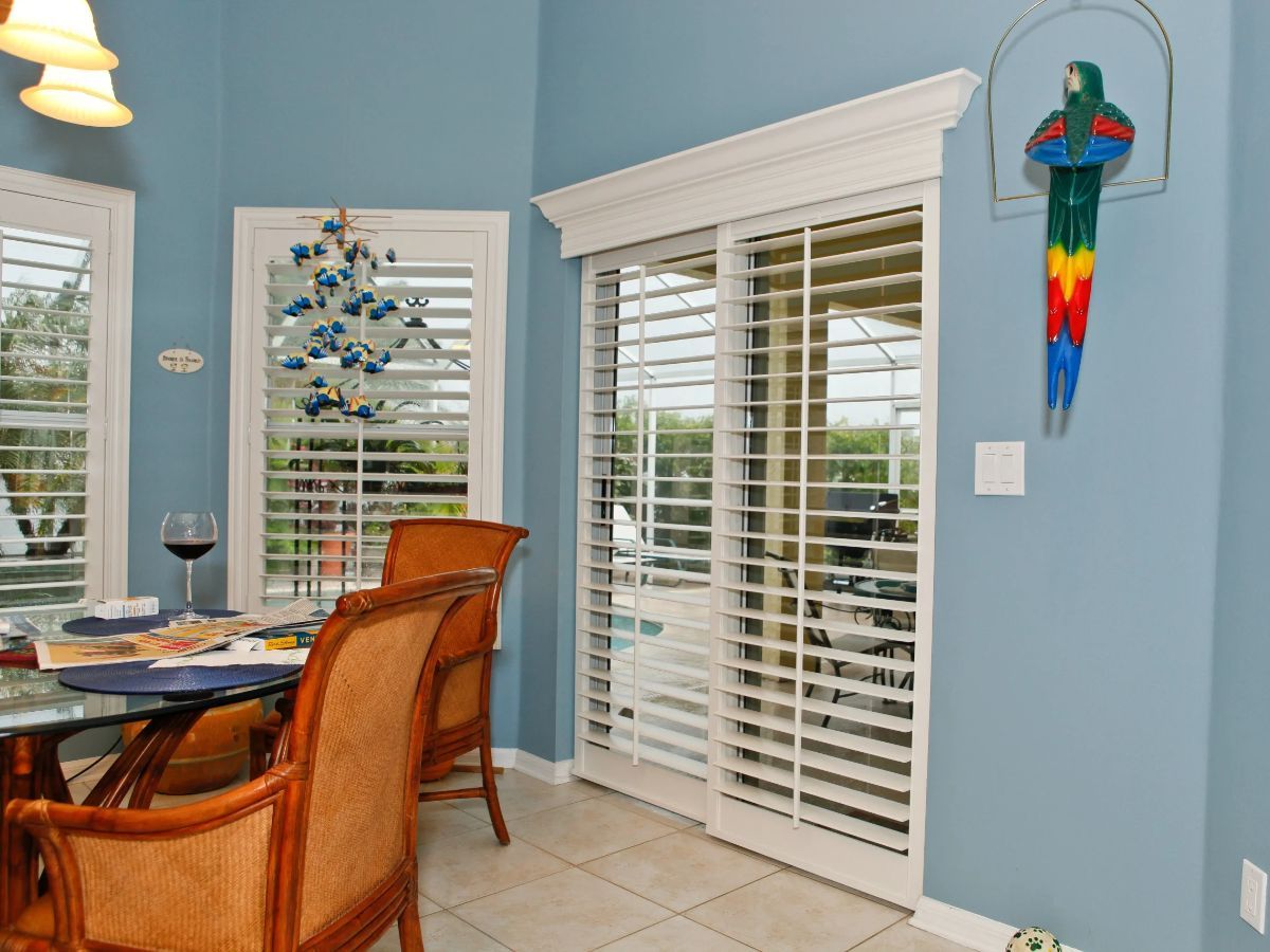 A dining room with a table and chairs and sliding glass doors