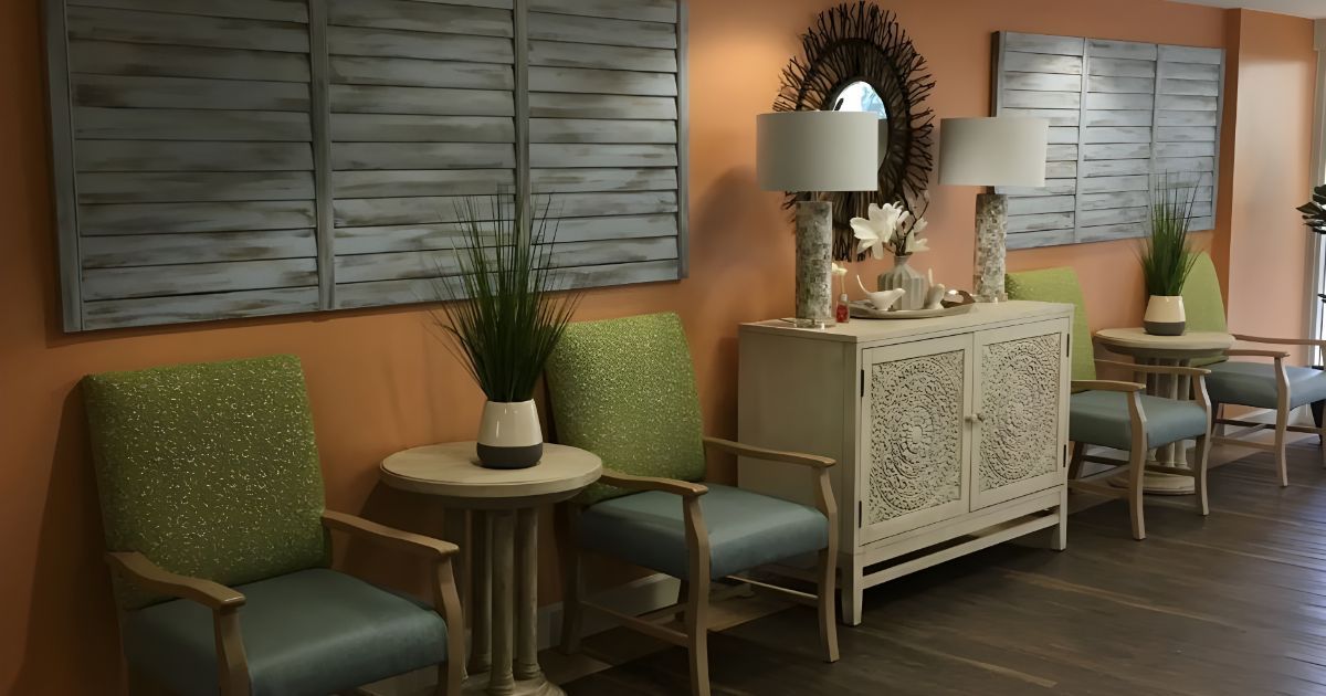 A waiting room with chairs , tables , lamps and a dresser.