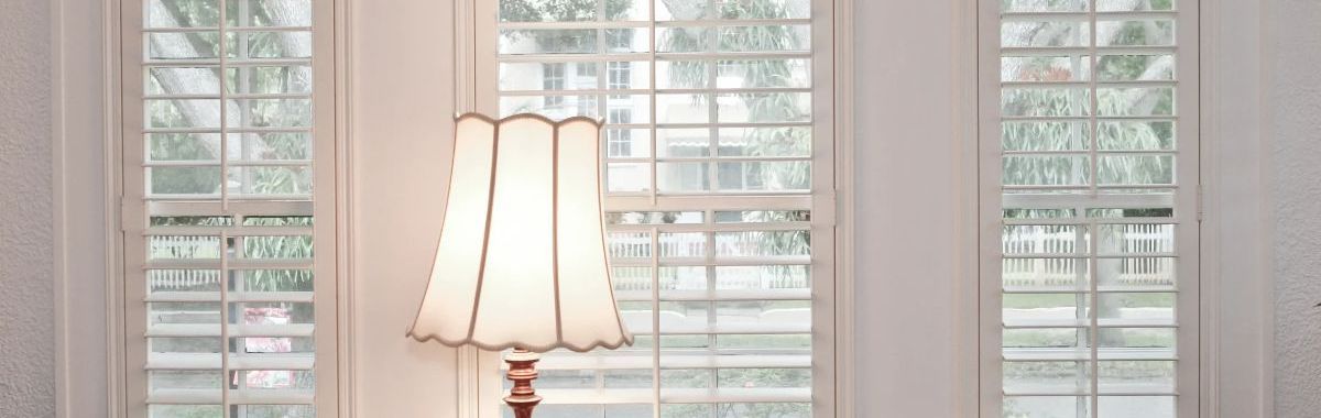 A lamp is sitting in front of a window in a living room.