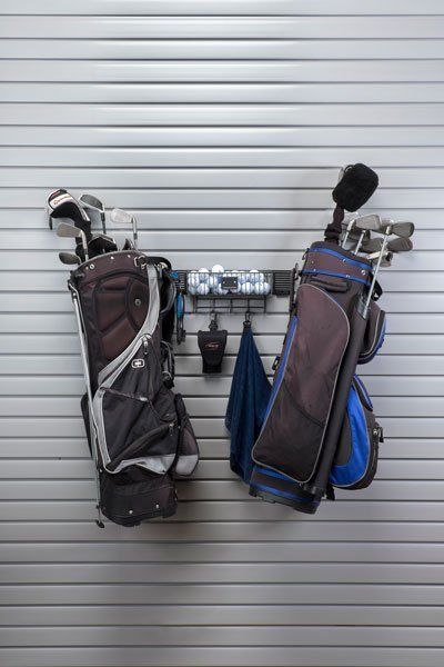 Two golf bags are hanging on a rack on a wall.