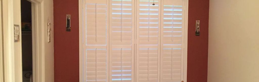 A room with red walls and white shutters on the doors.