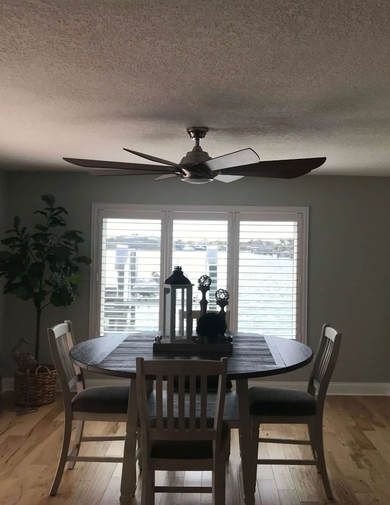 A dining room with a table and chairs and a ceiling fan.