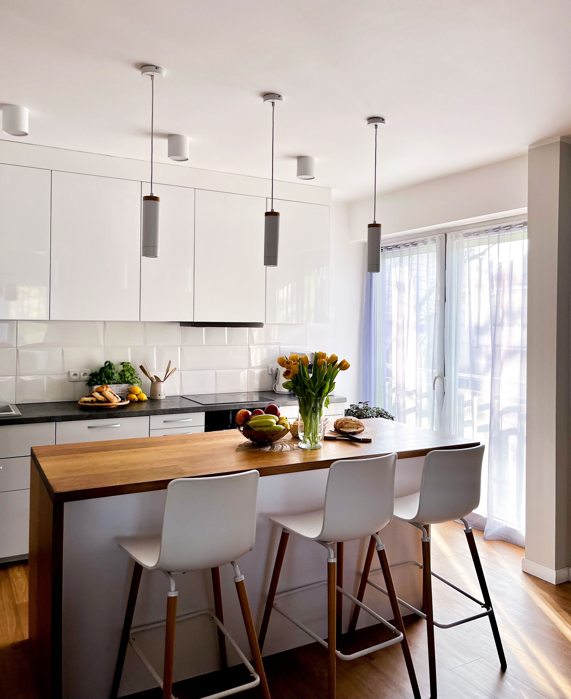 Kitchen with white cabinets, black appliances, gray countertops and wood-look flooring.