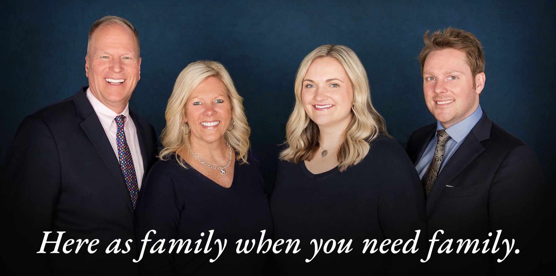 A group of people posing for a picture with the words here as family when you need family.