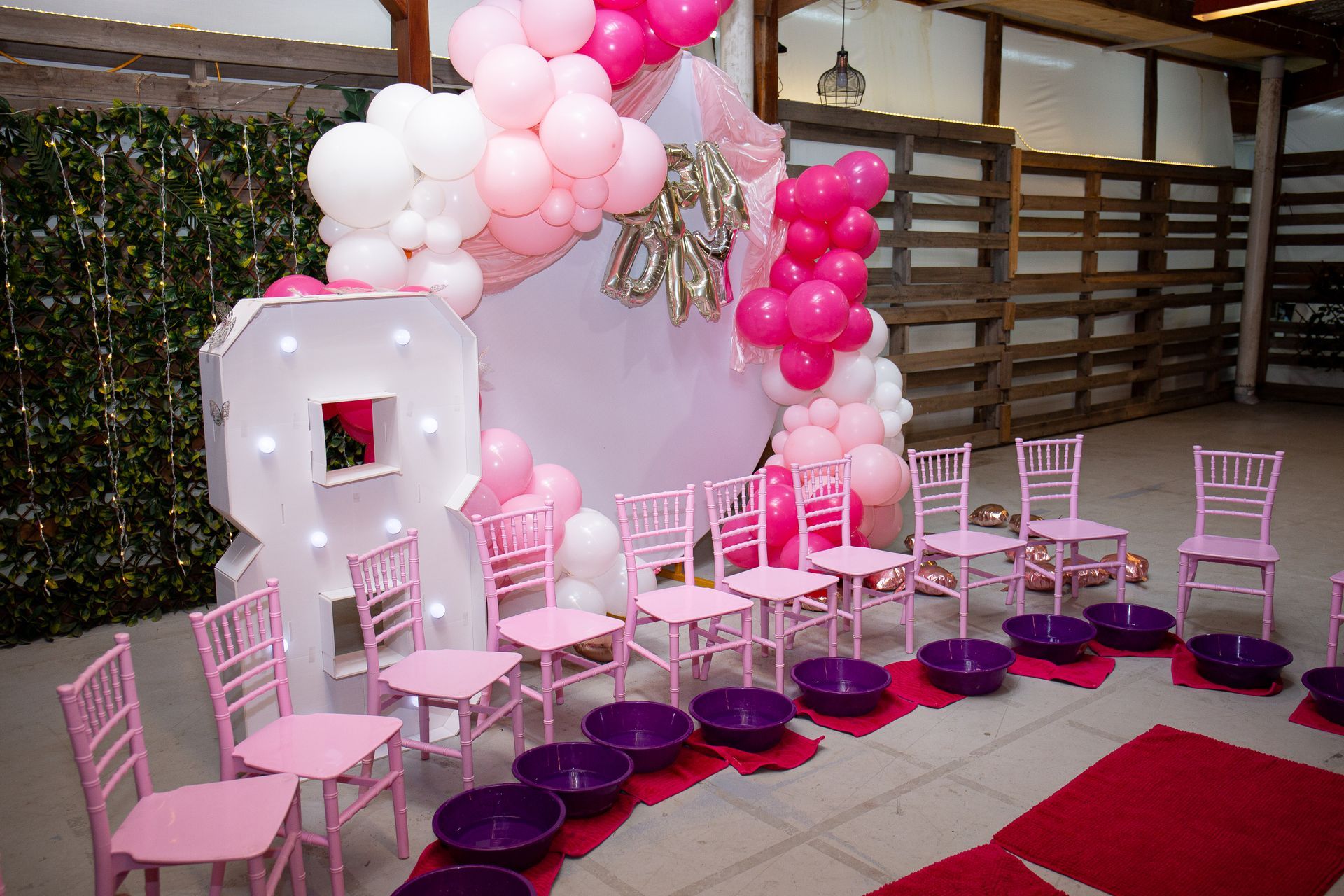 Pink and white party setup with balloon arch, number 