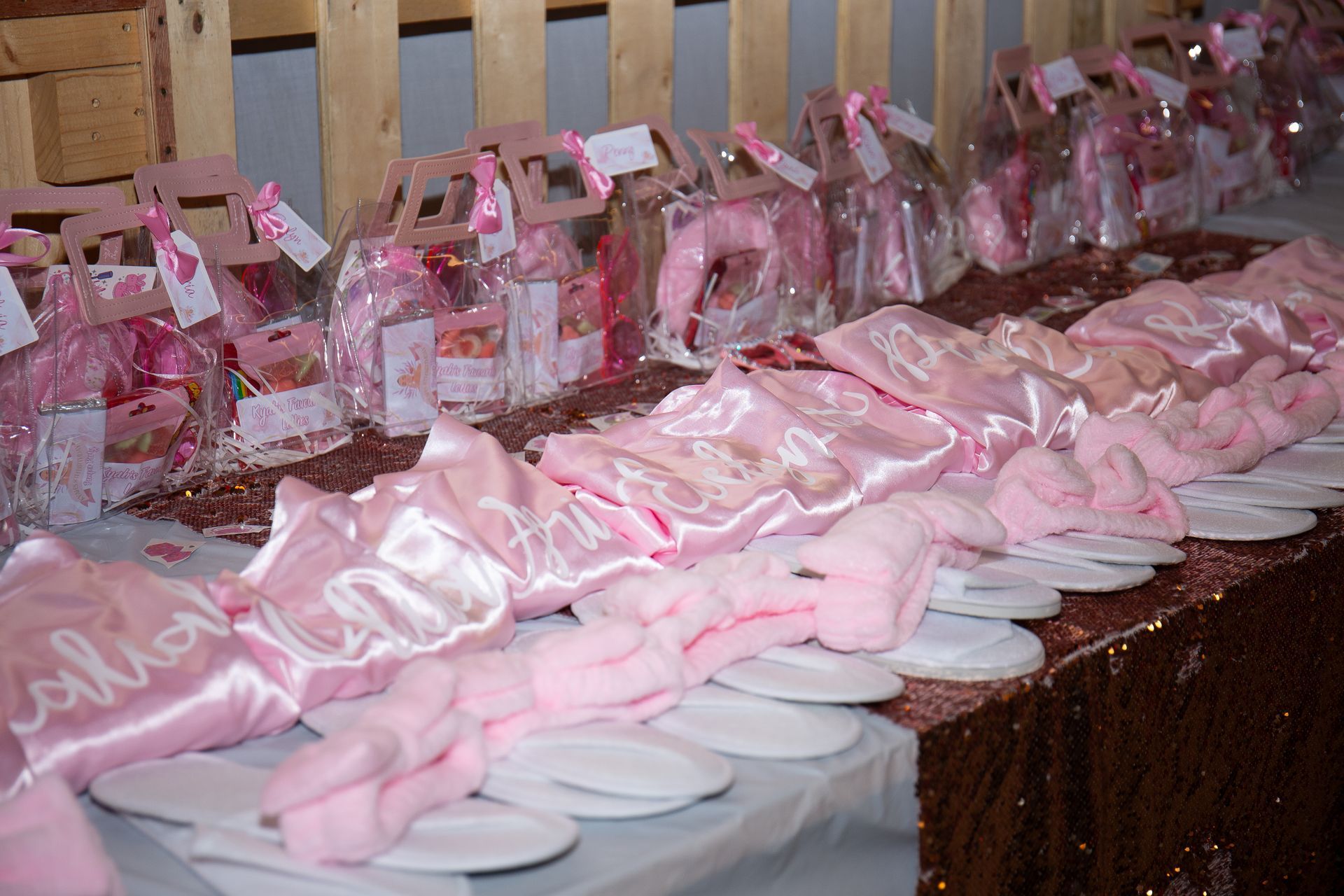 Pink gifts and robes with personalized names, displayed on a table.