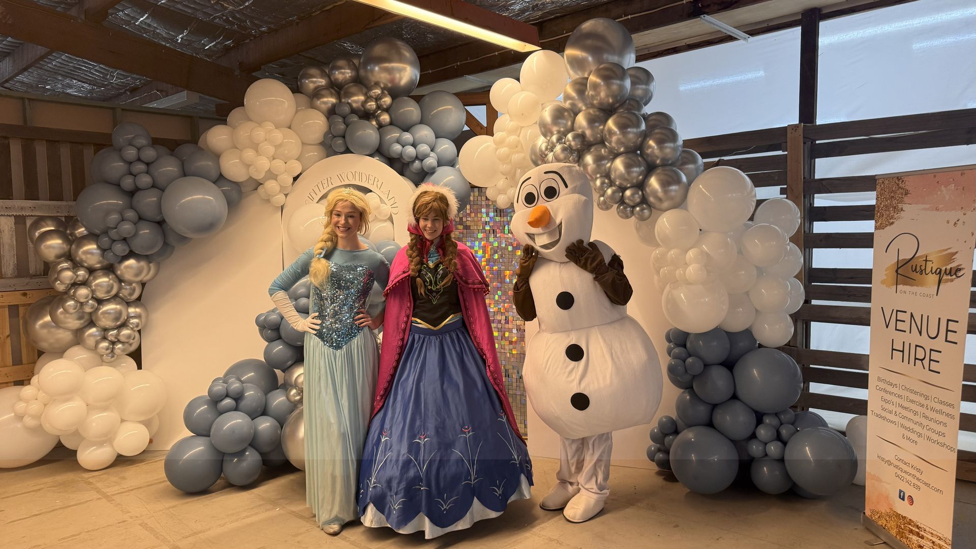 Three People in Costumes Pose With a Snowy Balloon Arch Backdrop — Rustique on the Coast In Ourimbah, NSW