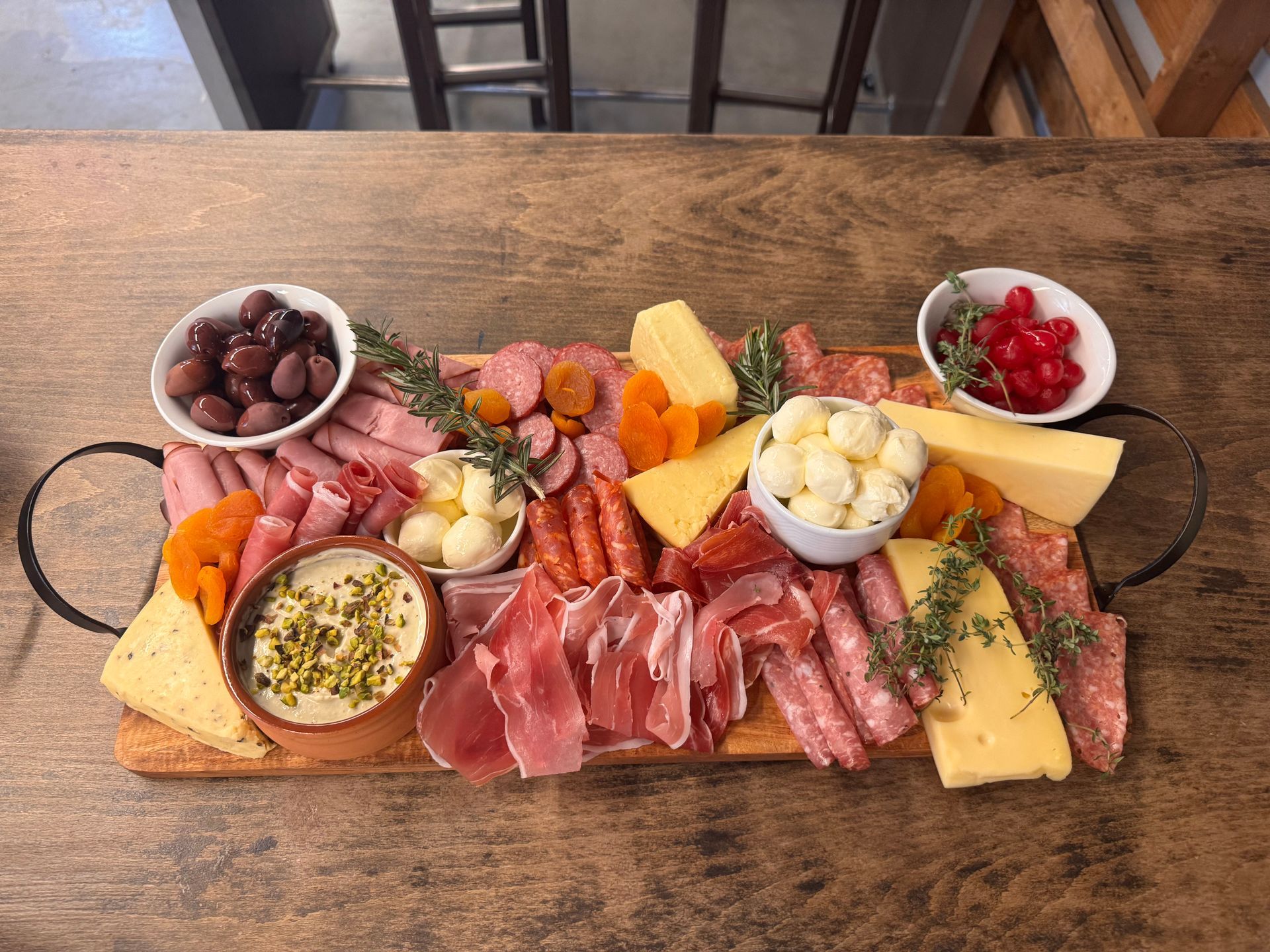 A rectangular wooden charcuterie board filled with various meats, cheeses, olives, dried fruit, and a creamy dip — Rustique on the Coast In Ourimbah, NSW