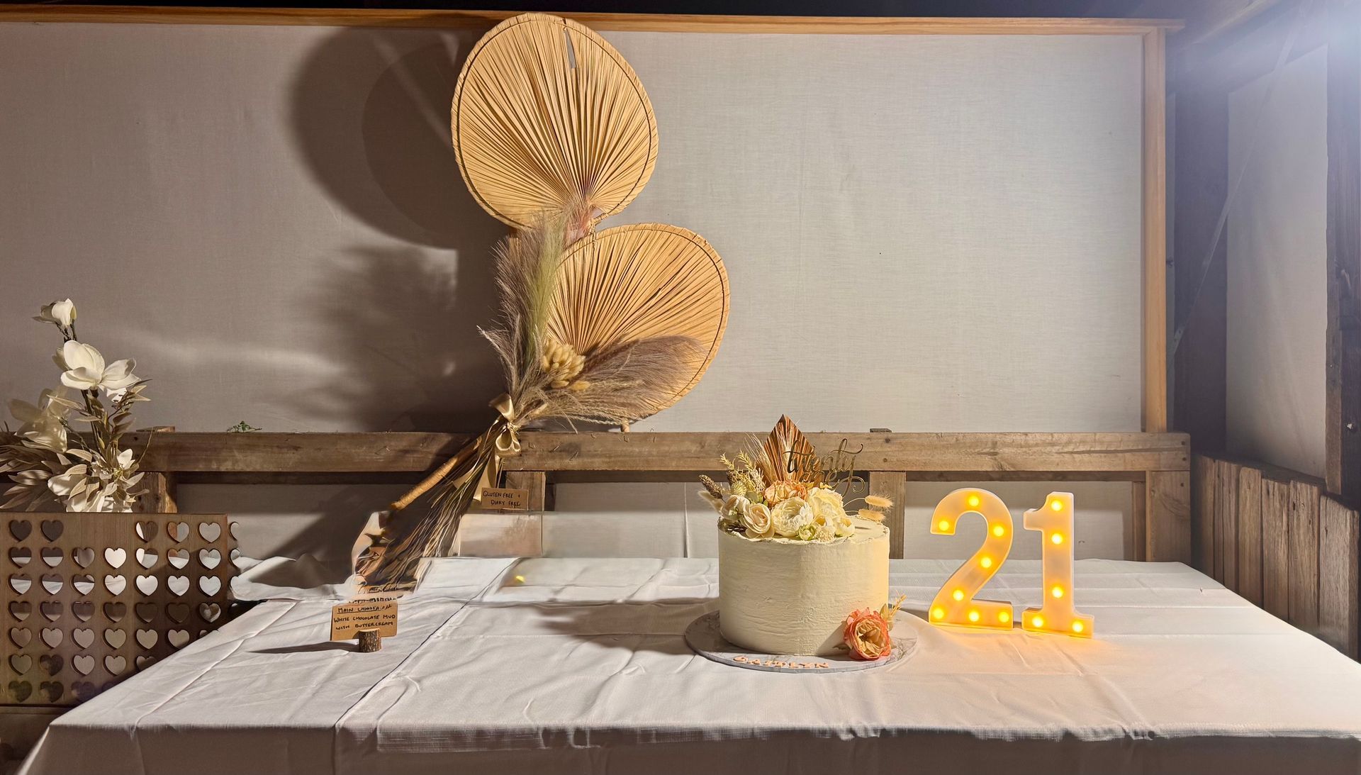 Table setting with decorative fans, vase with dried flowers, and lighted