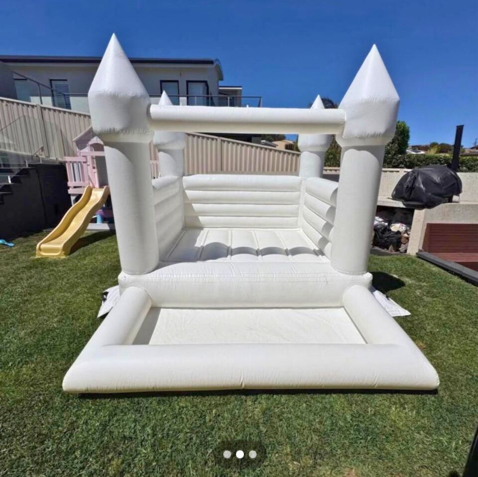 White inflatable bounce house in a backyard, with a slide visible