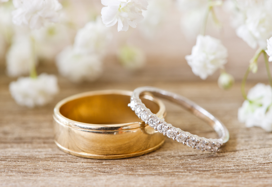 Wedding rings on wood surface with white flowers in the background — Rustique on the Coast In Ourimbah, NSW