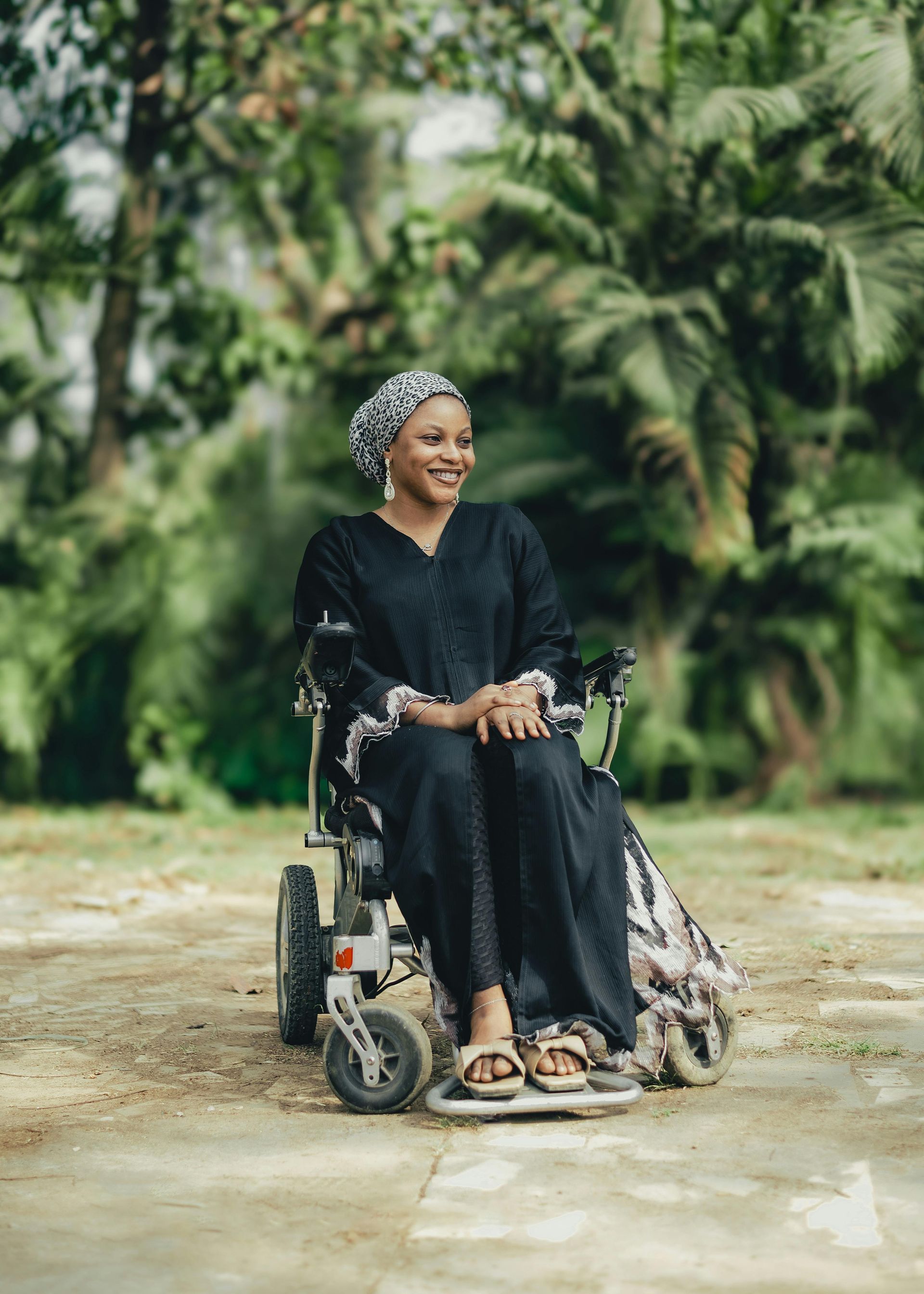A woman in a black dress is sitting in a wheelchair.