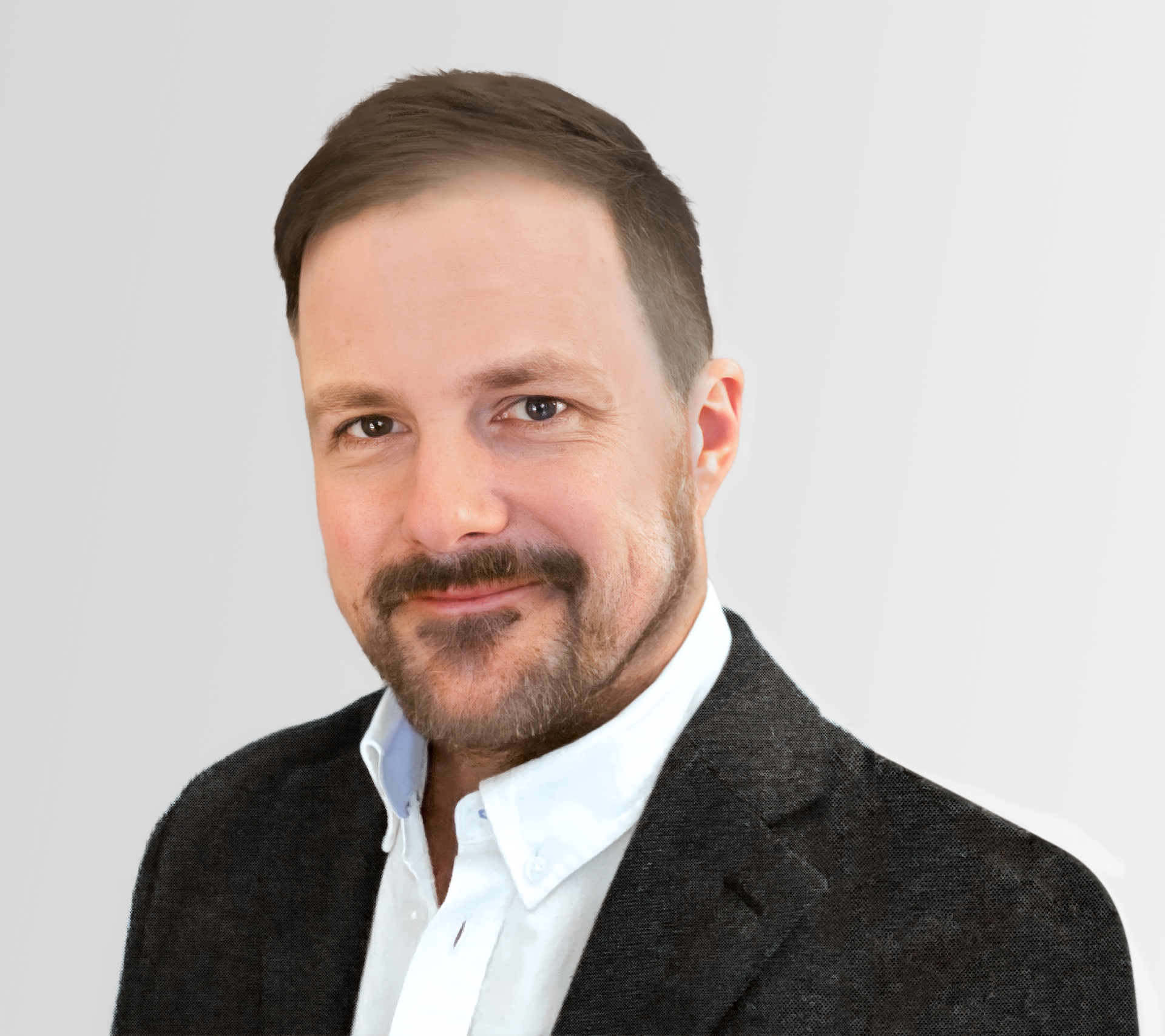 Man smiling, wearing a blue pinstripe shirt and dark blazer, against a light gray background.