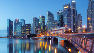 Skyscrapers with glass facades against a bright sun in a blue sky.