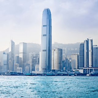 Hong Kong skyline with tall skyscrapers, including the International Finance Centre, overlooking the water on a hazy day.
