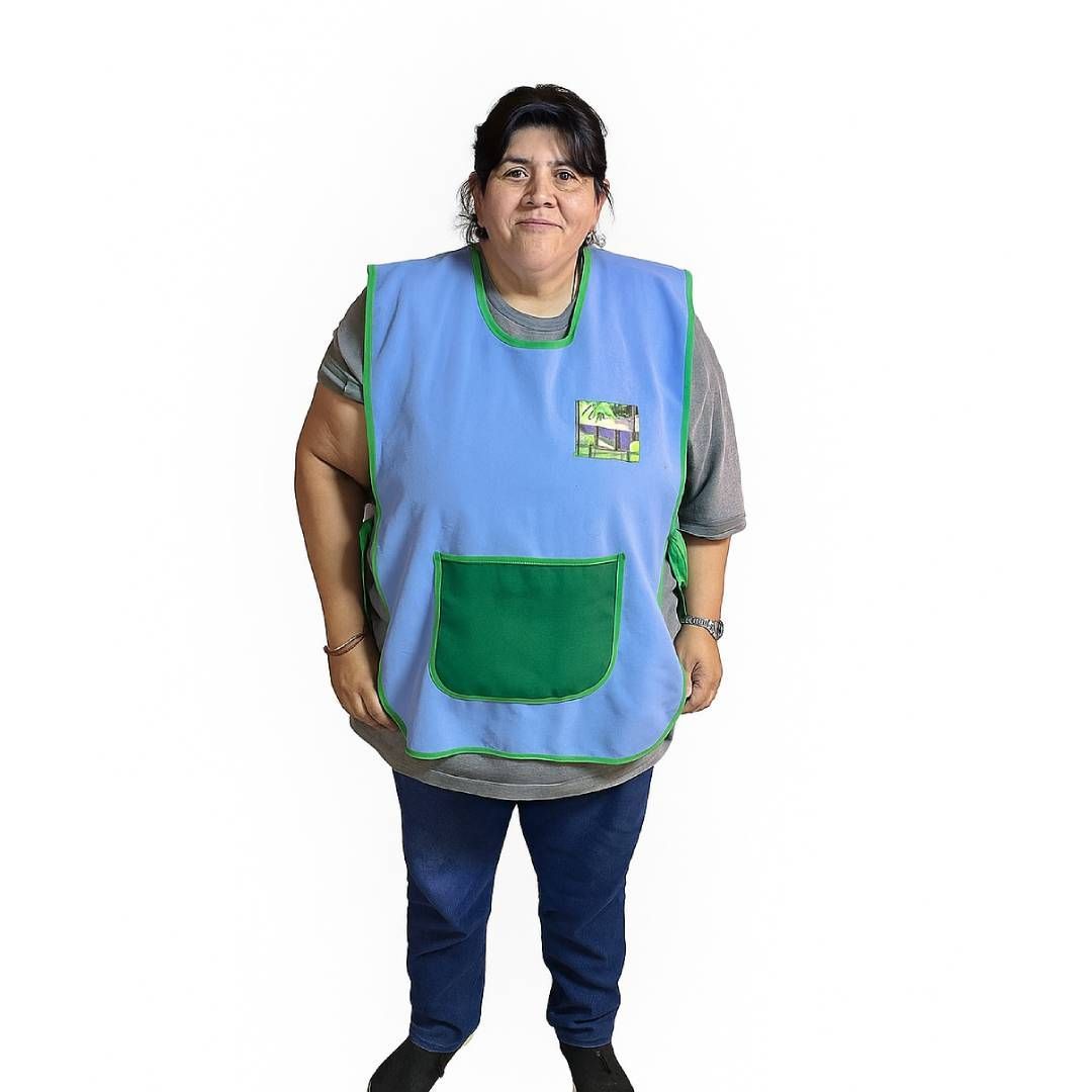 Una mujer con un delantal azul con bolsillo verde está parada en una cocina 