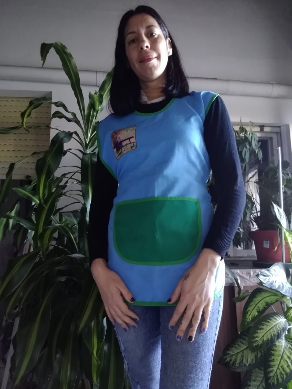 Mujer con delantal azul y jeans, sonriendo