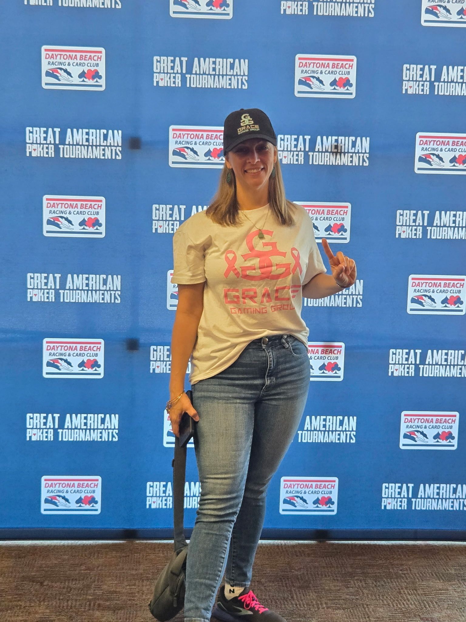 A woman is standing in front of a blue wall that says great american poker tournaments