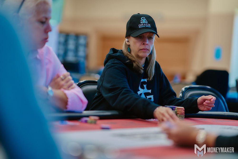 A woman is sitting at a table playing poker.