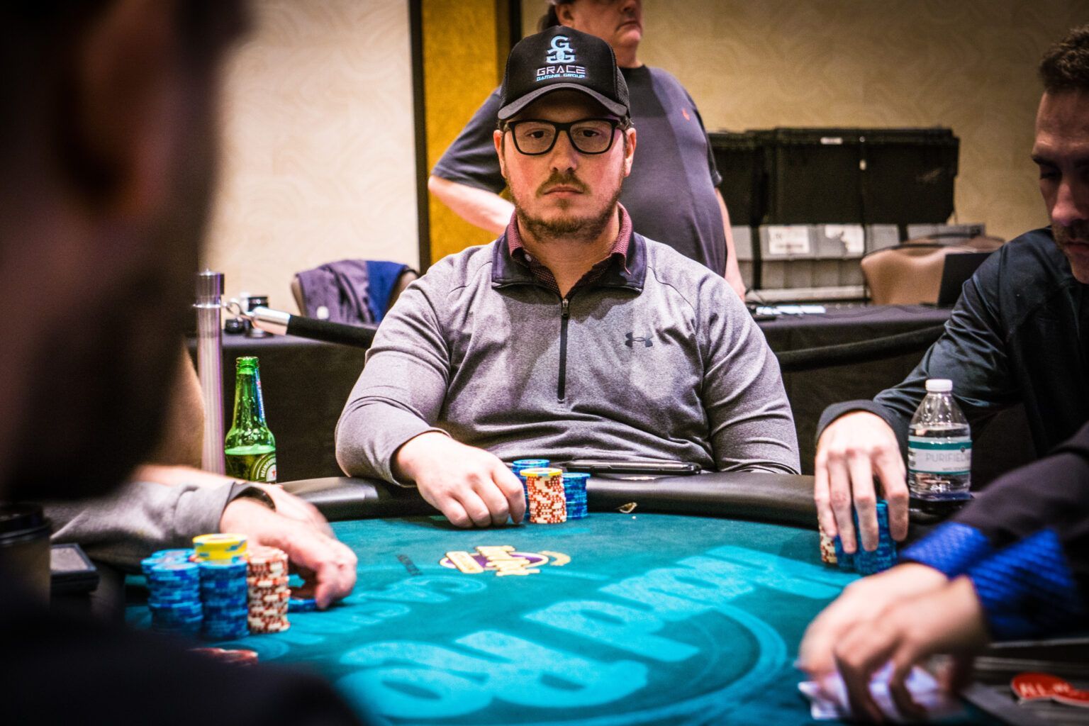 A man is sitting at a poker table with other people.