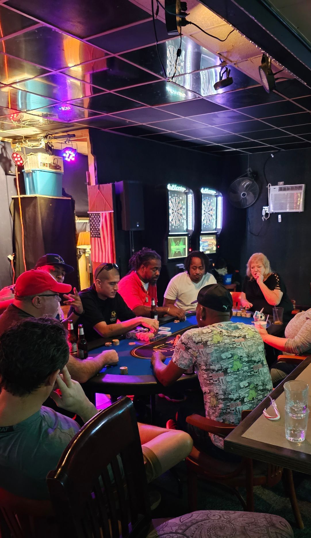 A group of people are sitting at tables in a dark room playing poker.