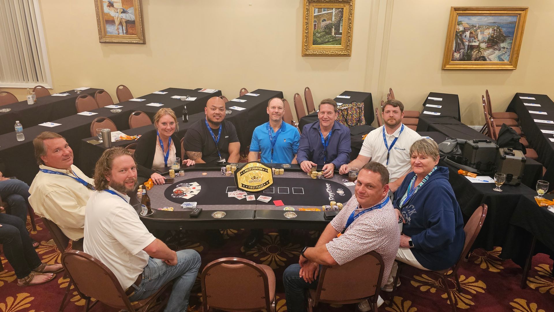 A group of people are sitting around a poker table.