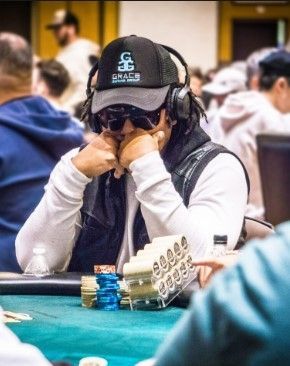 A man wearing headphones and a hat is sitting at a poker table.