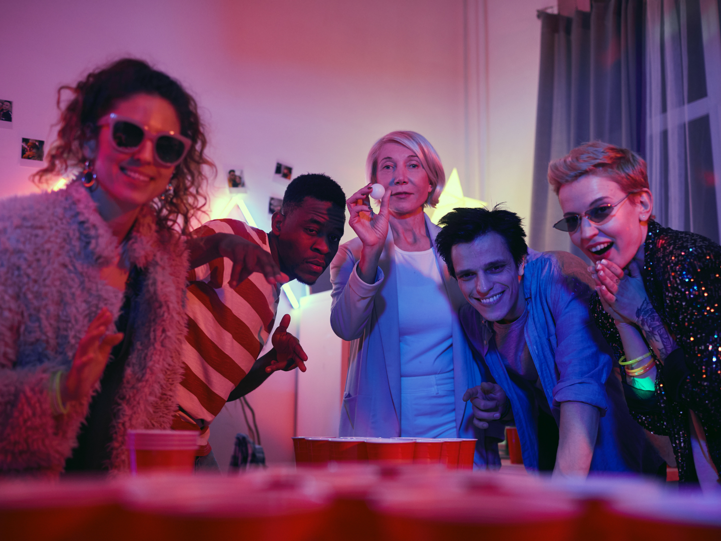 A group of young people are playing ping pong at a party.