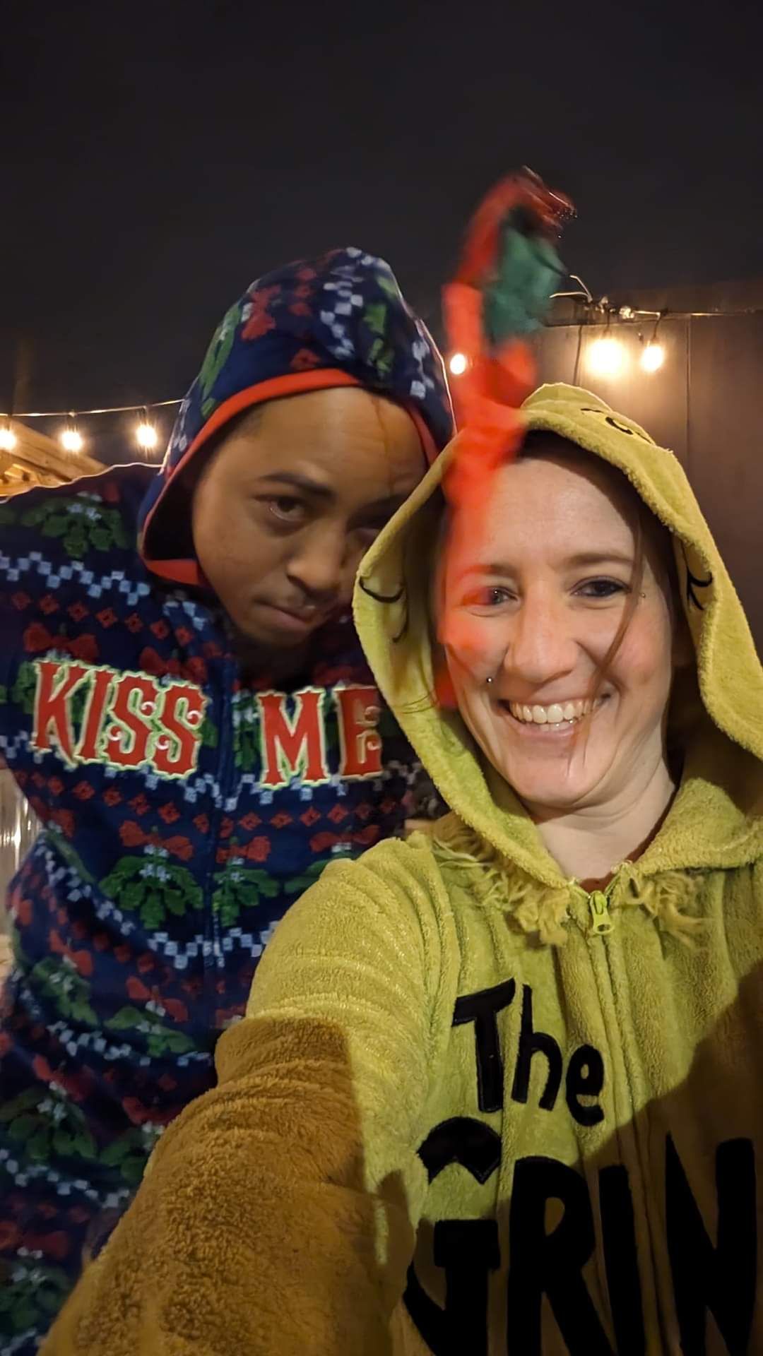 A man and a woman are posing for a selfie while wearing christmas sweaters.