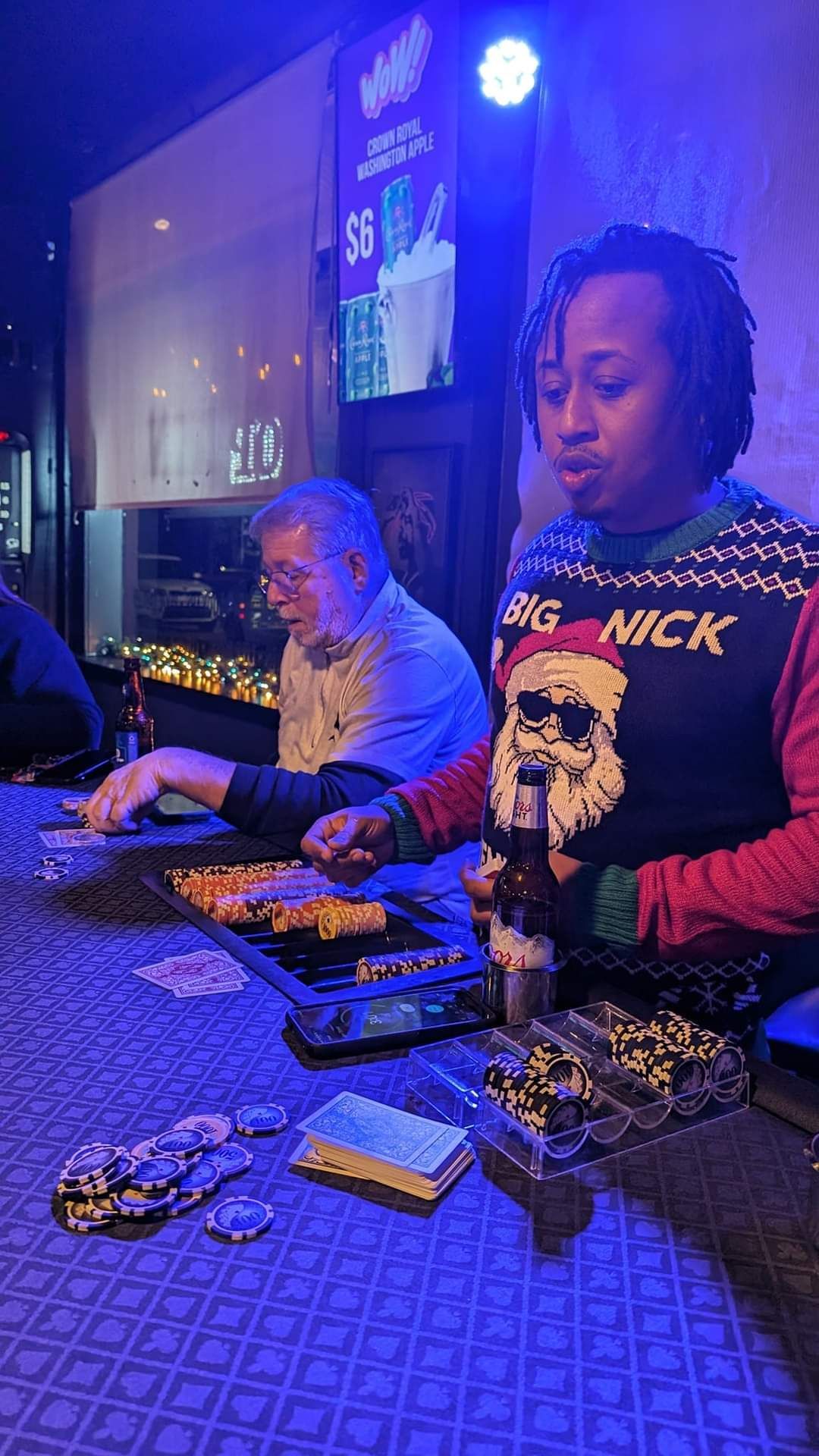 A group of people are sitting at a bar playing cards.