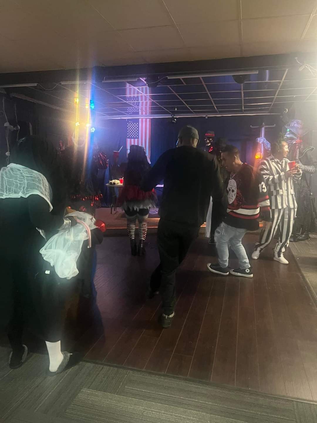 A group of people are dancing in a room at a halloween party.