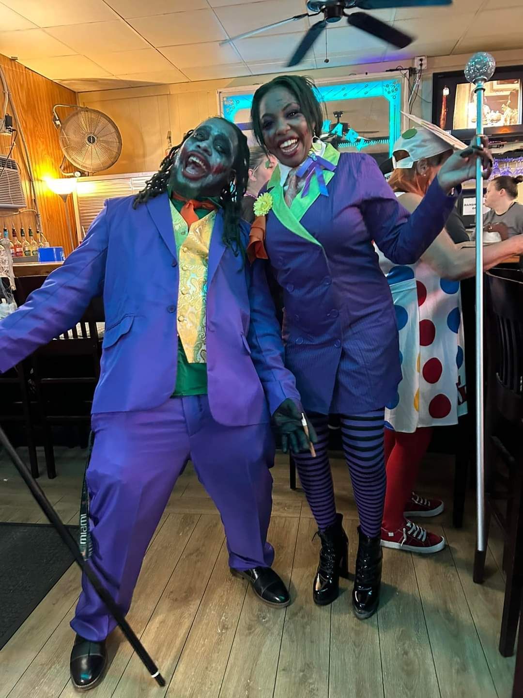 A man and a woman dressed as the joker are standing next to each other in a room.