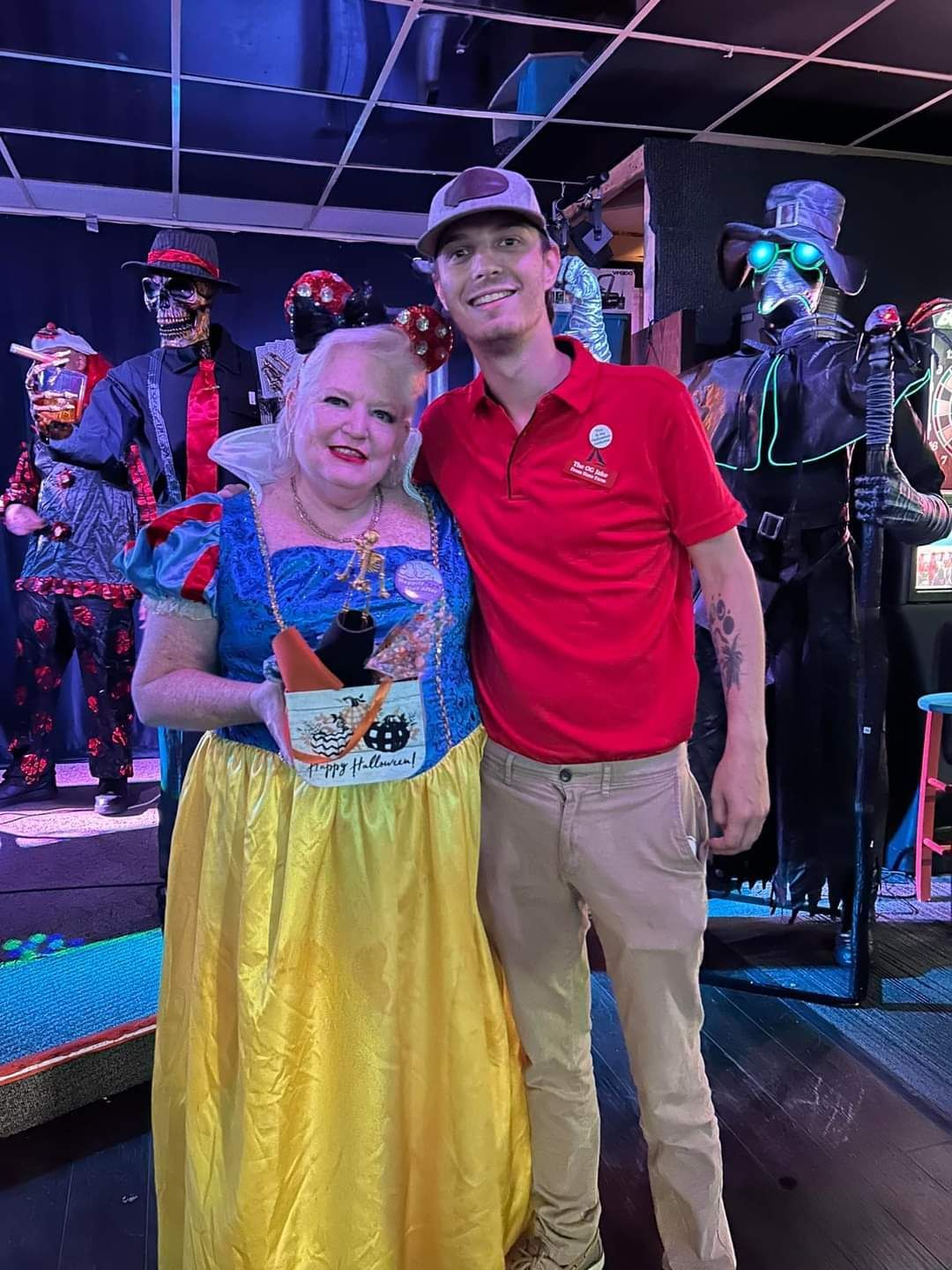 A woman in a snow white costume is posing for a picture with a man in a red shirt.