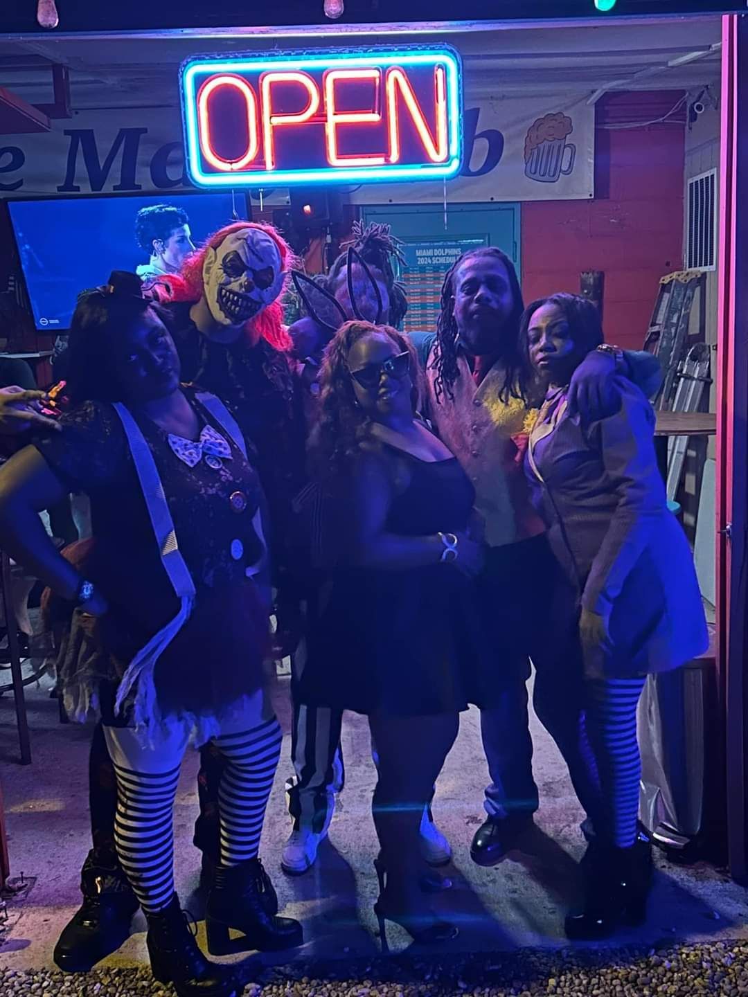 A group of people are posing for a picture in front of an open sign.