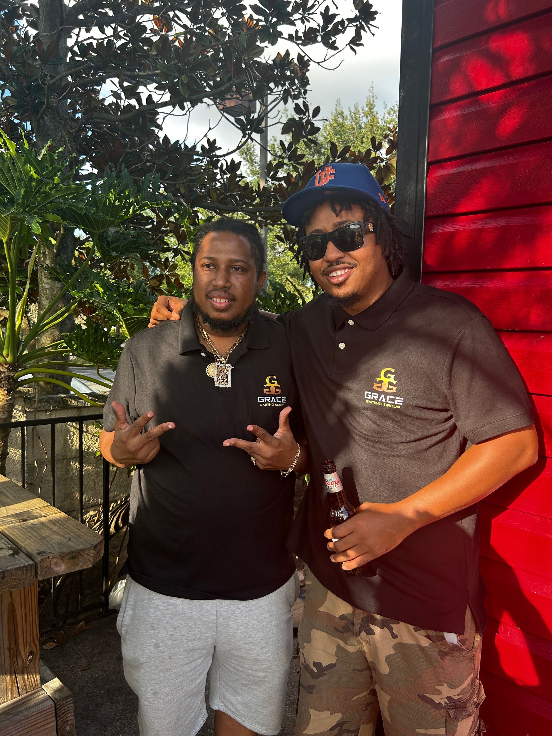 Two men standing next to each other in front of a red building