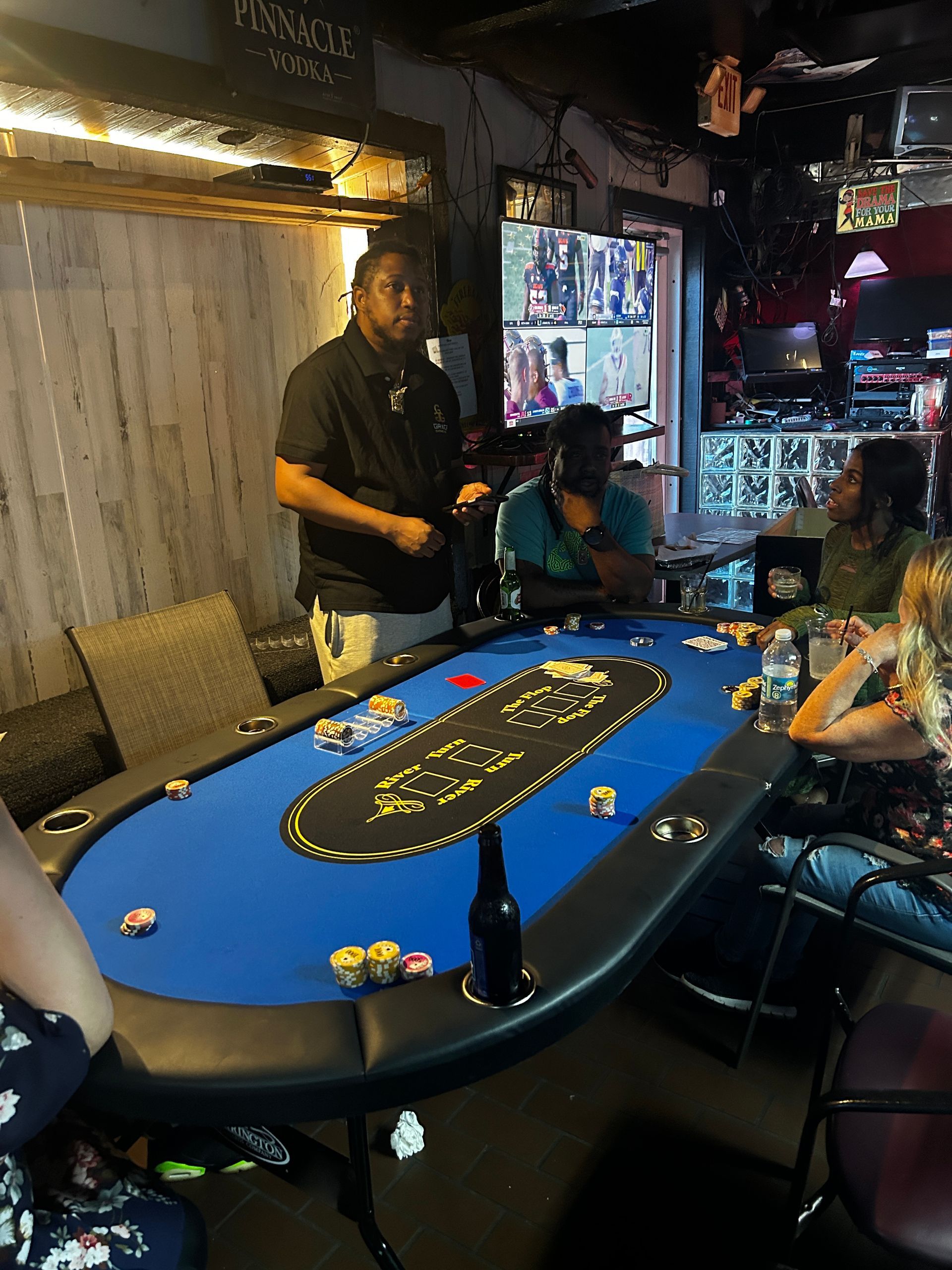 A group of people are sitting around a blue poker table.