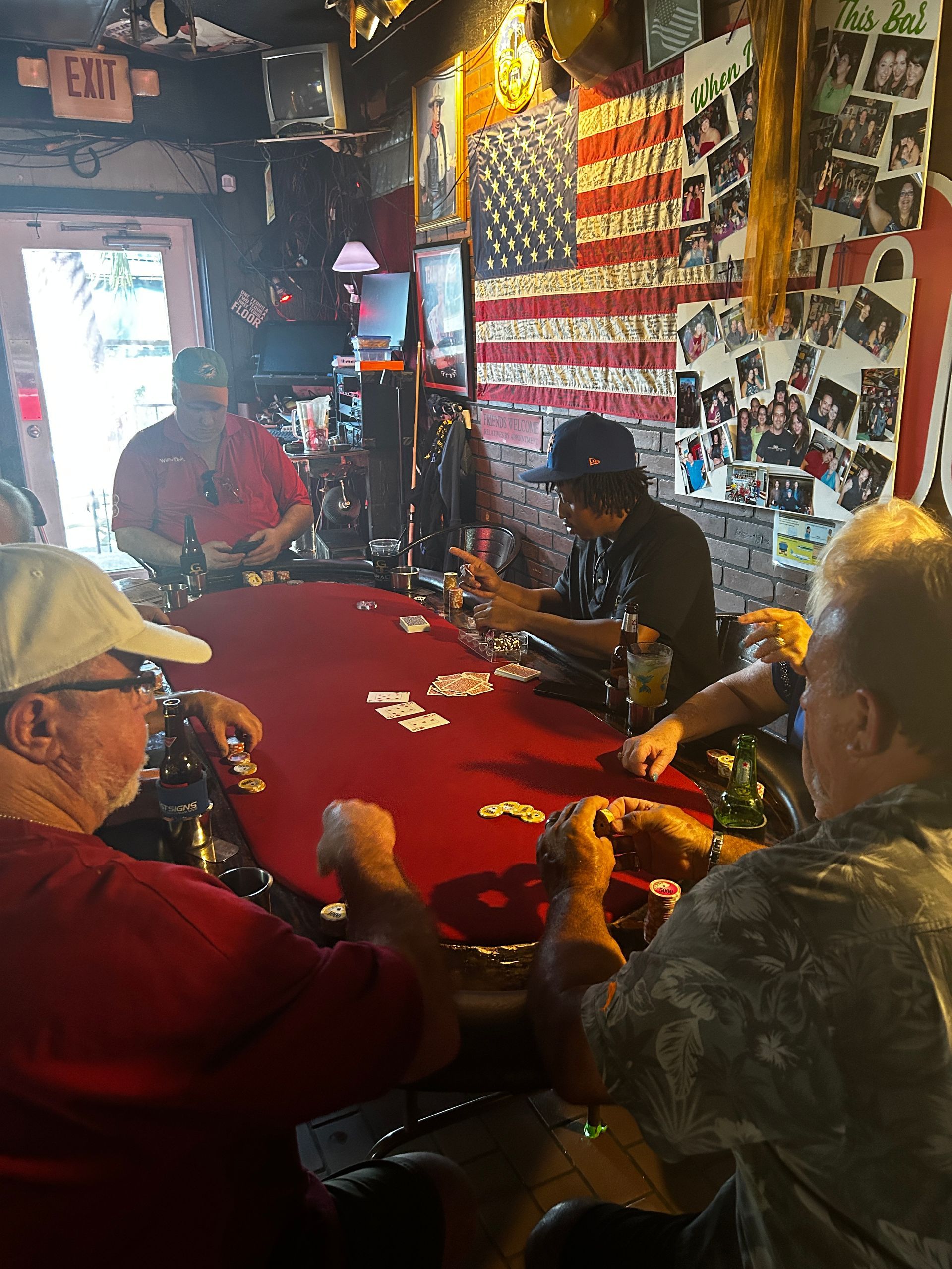 A group of men are playing cards at a table in a bar.