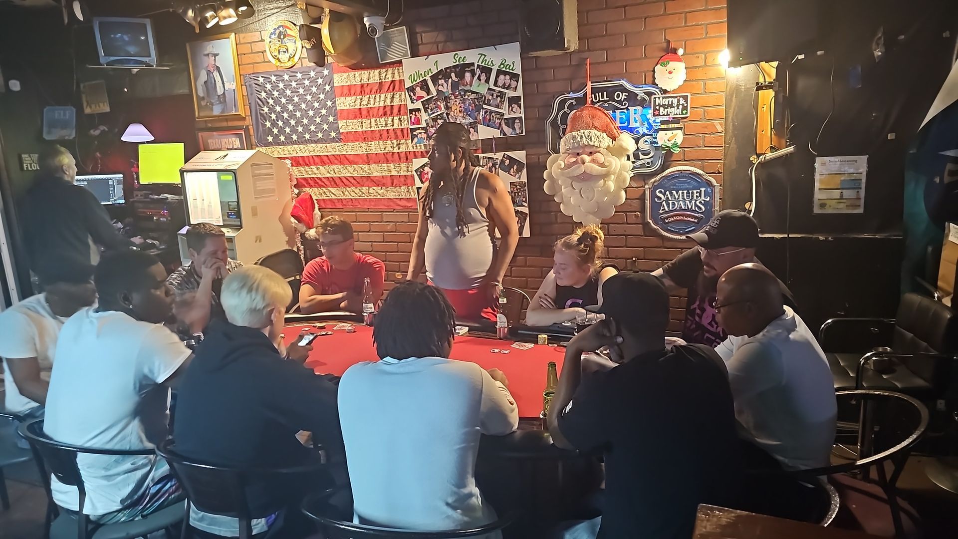 A group of people are sitting around a pool table in a bar.