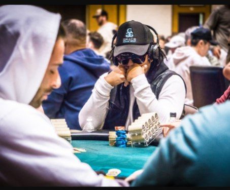 A man wearing a dodgers hat sits at a poker table
