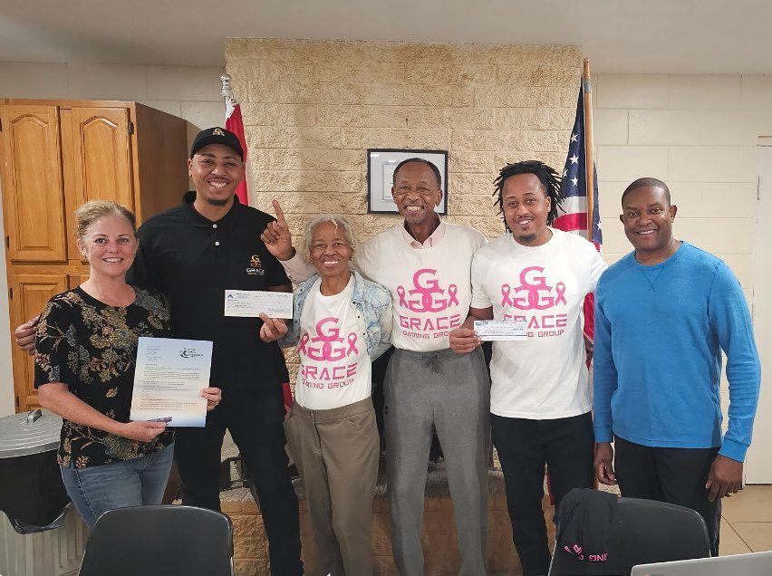 A group of people standing next to each other holding a check.