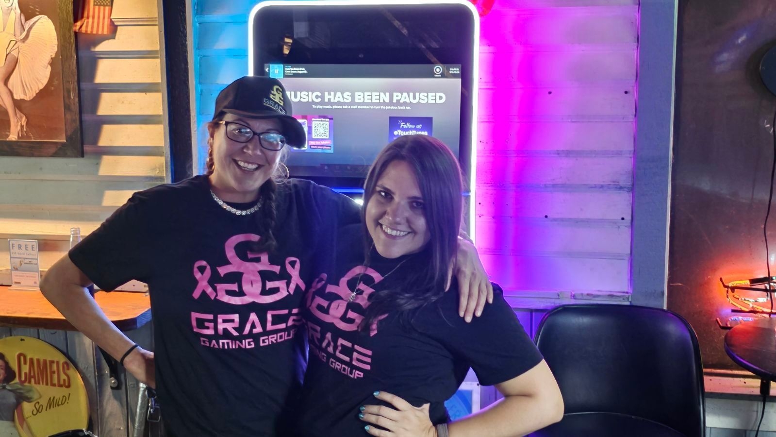 Two women are posing for a picture in front of a cell phone.
