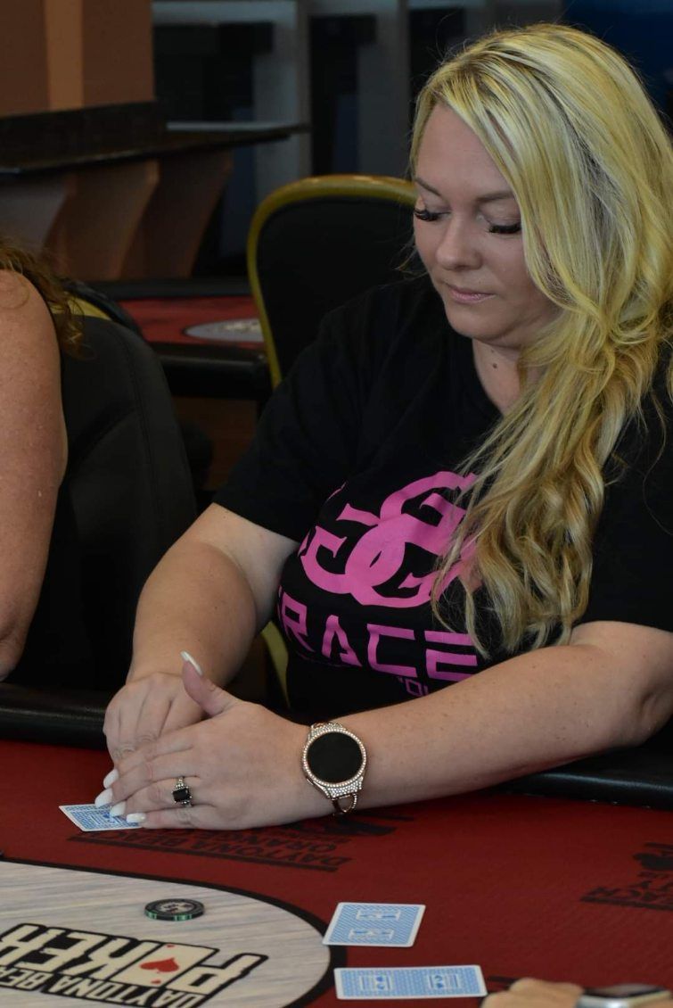 A woman is sitting at a table playing poker.