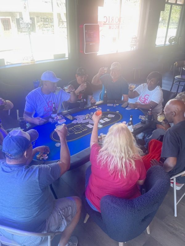 A group of people are sitting around a table playing cards.