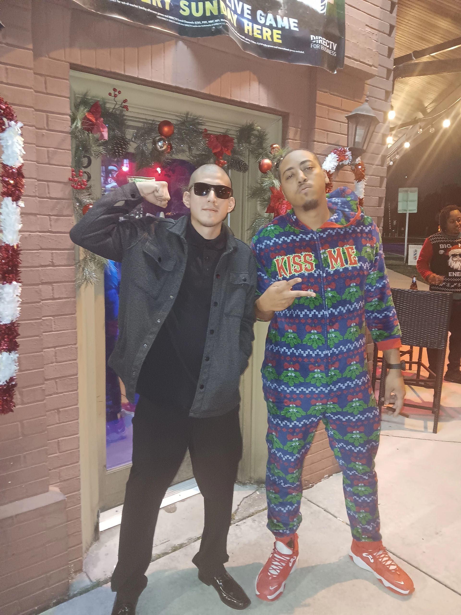 Two men are posing for a picture in front of a brick building